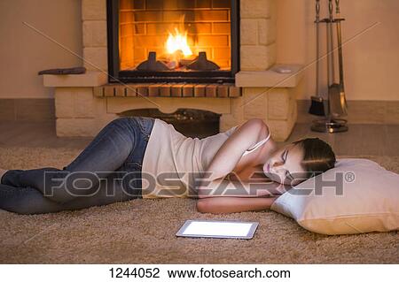 Beautiful woman relaxing by fire next to digital tablet View Large Photo Image Stock Image - Beautiful woman relaxing by fire next to digital tablet. Fotosearch