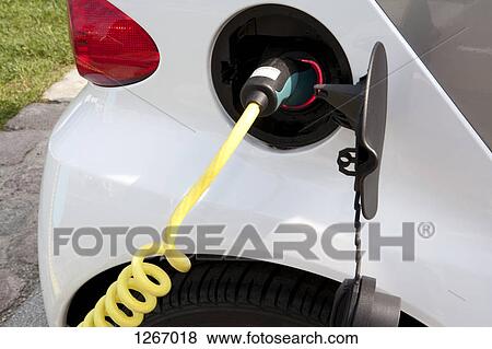 Stock Photo - Detail of a charger connected to an electric car recharging. Fotosearch