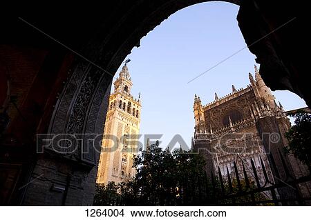 Picture - Exterior view of Seville Cathedral, including La Giralda from a darkened archway. Fotosearch