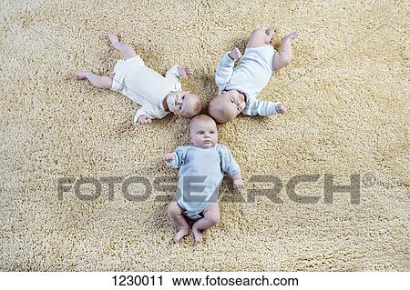 Formation of three babies laying on carpet View Large Photo Image Stock Image - Formation of three babies laying on carpet. Fotosearch