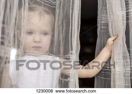 Girl looking out between curtains of open window View Large Photo Image Stock Photo - Girl looking out between curtains of open window. Fotosearch