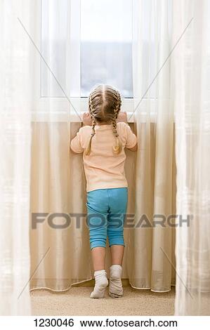 Little girl on her tiptoes trying to see out window View Large Photo Image Stock Photograph - Little girl on her tiptoes trying to see out window. Fotosearch