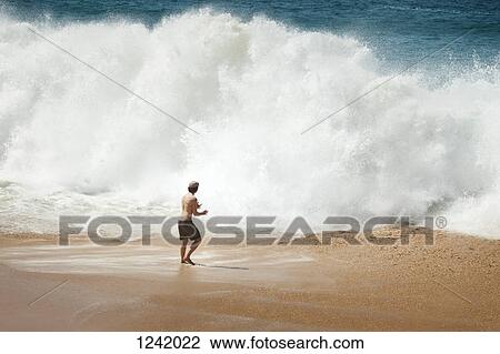 Man facing big wave on beach in La Graciosa, Canary Islands, Spain View Large Photo Image Stock Image - Man facing big wave on beach in La Graciosa, Canary Islands, Spain. Fotosearch