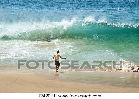 Man facing wave on beach in La Graciosa, Canary Islands, Spain View Large Photo Image Stock Image - Man facing wave on beach in La Graciosa, Canary Islands, Spain. Fotosearch