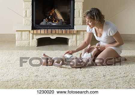 Stock Image - Mother and daughters on carpet in front of fire. Fotosearch