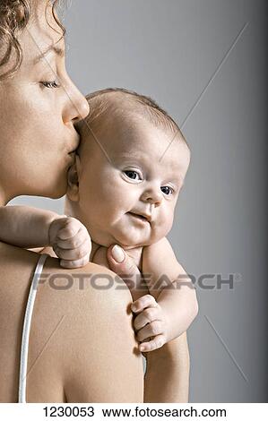 Stock Image - Mother kissing her child on the head. Fotosearch
