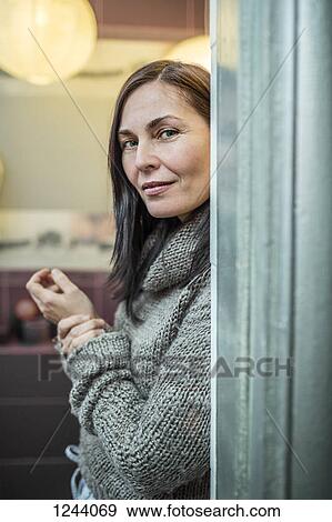Stock Photo - Portrait of woman holding her wrist and looking at camera. Fotosearch