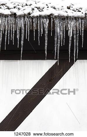 Stock Photo - Snow and a row of icicles hanging from the eaves of a building. Fotosearch