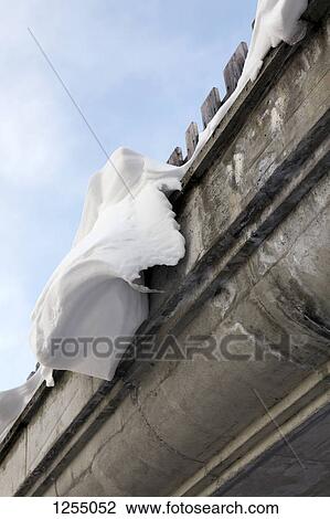 Stock Image - Snow on the eaves of a building, close-up, low angle view. Fotosearch