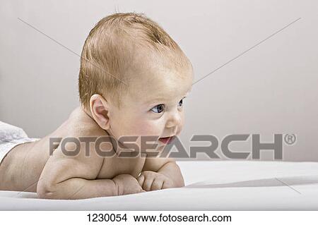 Studio shot of baby lying on bed View Large Photo Image Picture - Studio shot of baby lying on bed. Fotosearch