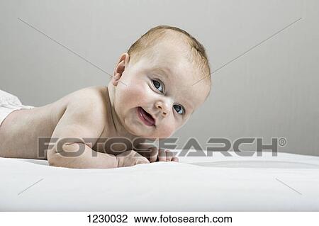 Studio shot of happy baby lying on bed View Large Photo Image Stock Image - Studio shot of happy baby lying on bed. Fotosearch
