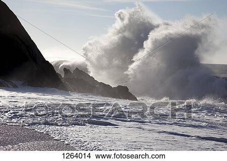 Sunlight shining on large waves crashing against rocks View Large Photo Image Picture - Sunlight shining on large waves crashing against rocks. Fotosearch
