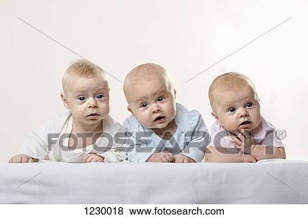 Stock Photo - Three babies in a row pulling funny faces. Fotosearch