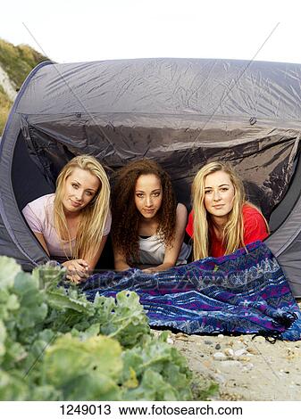 Three friends lying in a tent looking serenely into the camera View Large Photo Image Stock Image - Three friends lying in a tent looking serenely into the camera. Fotosearch