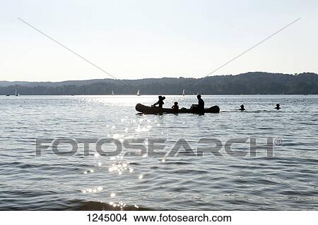 Three people in a canoe passing two swimmers at Starnberger Sea, Bavaria, Germany View Large Photo Image Picture - Three people in a canoe passing two swimmers at Starnberger Sea, Bavaria, Germany. Fotosearch