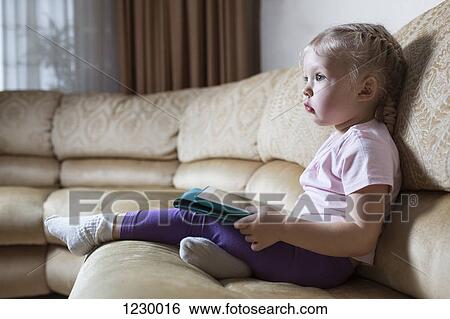 Transfixed girl on sofa with digital tablet View Large Photo Image Stock Photograph - Transfixed girl on sofa with digital tablet. Fotosearch