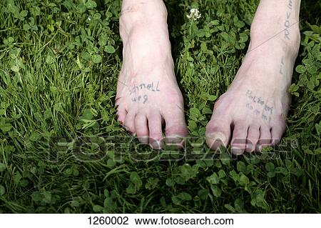 Stock Image - Two bare feet with faded tattoos on them. Fotosearch