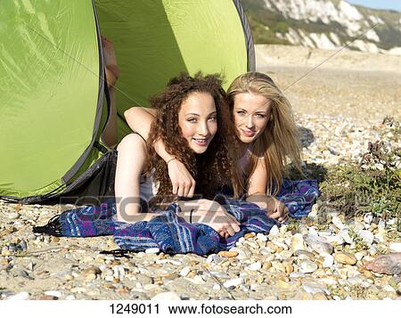 Two friends lying partially inside a beach tent on a rocky beach View Large Photo Image Stock Image - Two friends lying partially inside a beach tent on a rocky beach. Fotosearch