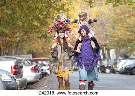 Stock Photo - Two mothers with their daughters on their shoulders in Prenzlauer Berg, Berlin, Germany. Fotosearch