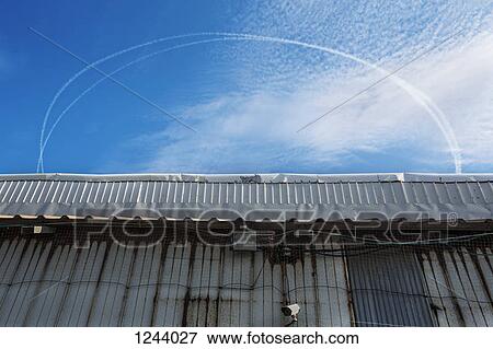 Vapor trail rings above a building with a surveillance camera View Large Photo Image Stock Photo - Vapor trail rings above a building with a surveillance camera . Fotosearch