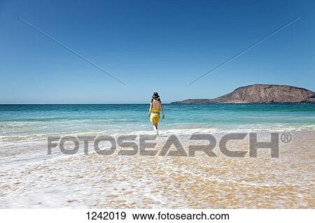 Woman walking through water on beach in La Graciosa, Canary Islands, Spain View Large Photo Image Stock Photo - Woman walking through water on beach in La Graciosa, Canary Islands, Spain. Fotosearch