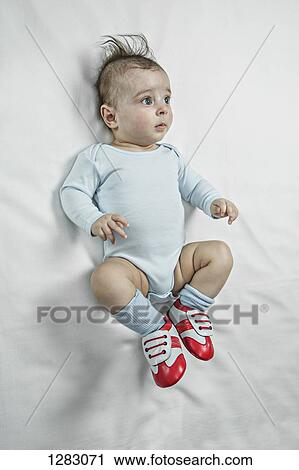 Stock Image - A baby boy wearing baby soccer shoes and looking contemplative. Fotosearch