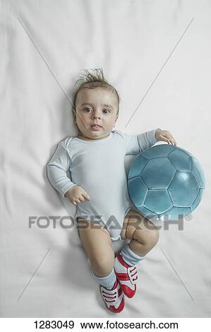 A baby boy wearing baby soccer shoes lying next to a soccer ball View Large Photo Image Stock Photo - A baby boy wearing baby soccer shoes lying next to a soccer ball. Fotosearch