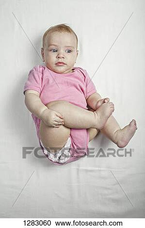 A baby girl lying on her back touching her barefoot curiously View Large Photo Image Stock Image - A baby girl lying on her back touching her barefoot curiously. Fotosearch