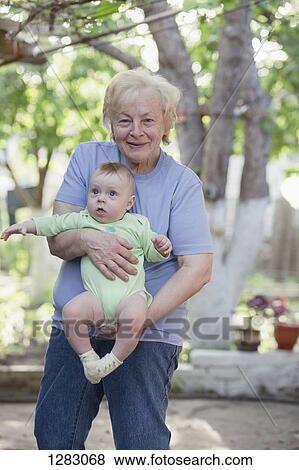 Stock Photo - A cheerful grandmother holding her grandson . Fotosearch