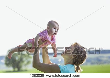 A cheerful mother holding her baby aloft View Large Photo Image Stock Photo - A cheerful mother holding her baby aloft. Fotosearch