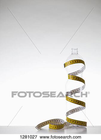 A disappearing plastic water bottle wrapped with a tape measure View Large Photo Image Stock Photo - A disappearing plastic water bottle wrapped with a tape measure. Fotosearch