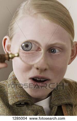 A girl looking surprised as she looks through a magnifying glass View Large Photo Image Picture - A girl looking surprised as she looks through a magnifying glass. Fotosearch