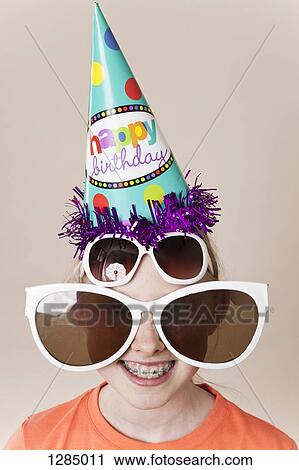 A girl wearing a pair of large novelty sunglasses, a normal pair of sunglasses and a party hat View Large Photo Image Stock Image - A girl wearing a pair of large novelty sunglasses, a normal pair of sunglasses and a party hat. Fotosearch