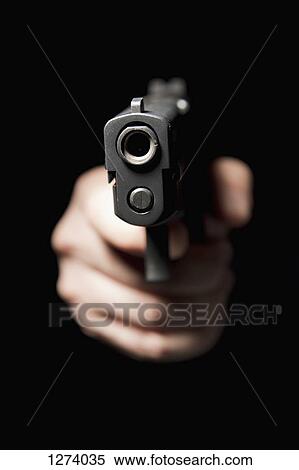 A hand holding a gun and pointing it at the camera, black background View Large Photo Image Stock Photography - A hand holding a gun and pointing it at the camera, black background. Fotosearch