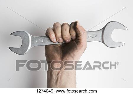 Stock Photo - A hand holding a wrench up triumphantly . Fotosearch