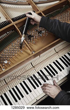 A repairman working on a grand piano View Large Photo Image Stock Photo - A repairman working on a grand piano. Fotosearch