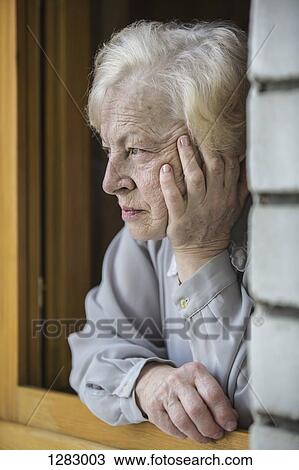 A senior woman leaning on a window sill, looking contemplative View Large Photo Image Stock Image - A senior woman leaning on a window sill, looking contemplative. Fotosearch