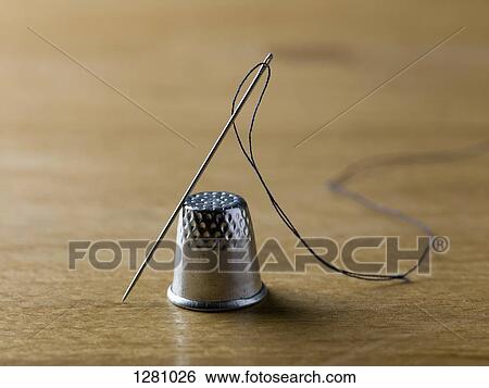 A threaded needle balanced against a shiny metal thimble View Large Photo Image Stock Photograph - A threaded needle balanced against a shiny metal thimble. Fotosearch