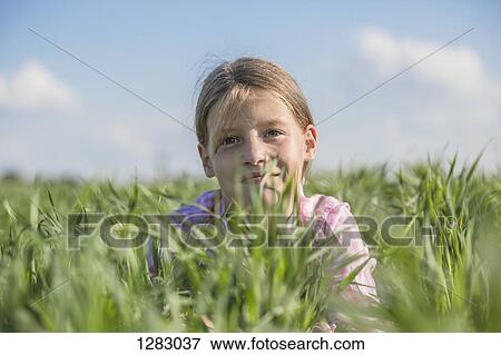 A young smiling girl lying in the grass on a summer's day View Large Photo Image Stock Photo - A young smiling girl lying in the grass on a summer's day. Fotosearch