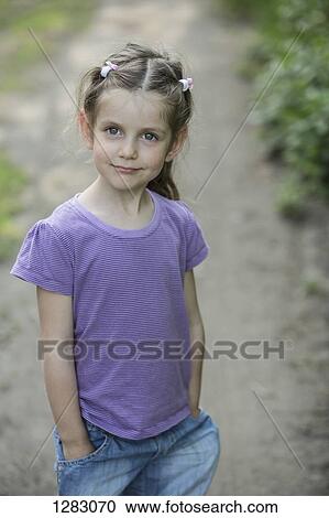 A young smiling girl standing on a dirt road View Large Photo Image Stock Image - A young smiling girl standing on a dirt road. Fotosearch