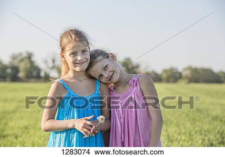 Affectionate twin sisters standing in a sunny field View Large Photo Image Picture - Affectionate twin sisters standing in a sunny field. Fotosearch