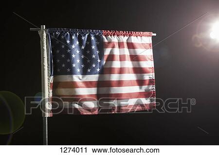 Stock Image - An American flag against a black background, spot lit. Fotosearch