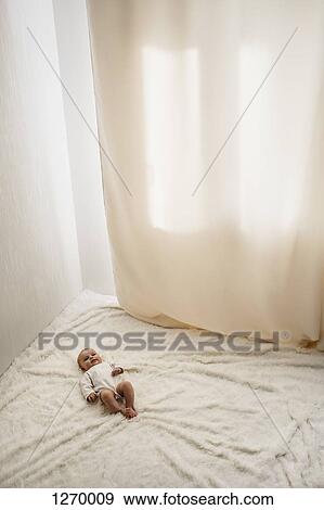 Stock Photo - Baby on white fur blanket. Fotosearch
