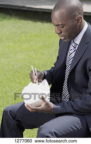 Businessman eating take away food with chop sticks outside View Large Photo Image Stock Image - Businessman eating take away food with chop sticks outside. Fotosearch