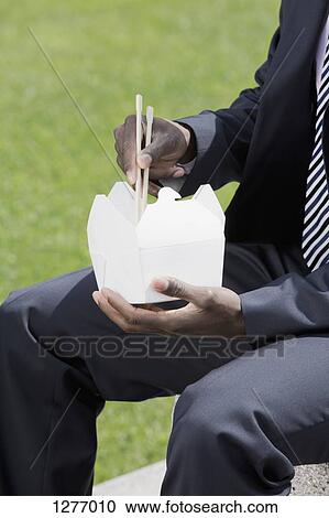 Businessman eating takeaway food with chop sticks View Large Photo Image Stock Image - Businessman eating takeaway food with chop sticks. Fotosearch