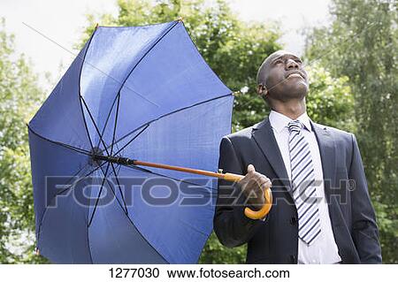 Businessman holding umbrella realising the rain has stopped View Large Photo Image Stock Image - Businessman holding umbrella realising the rain has stopped. Fotosearch