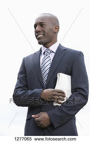 Businessman with newspaper underarm View Large Photo Image Stock Photography - Businessman with newspaper underarm. Fotosearch