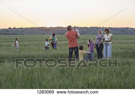 Families relaxing in a field in a rural setting View Large Photo Image Stock Photo - Families relaxing in a field in a rural setting. Fotosearch