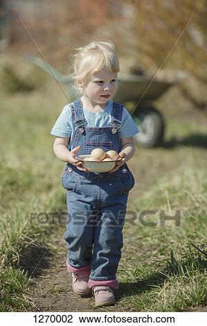 Stock Image - Farmer girl carrying bowl of eggs. Fotosearch
