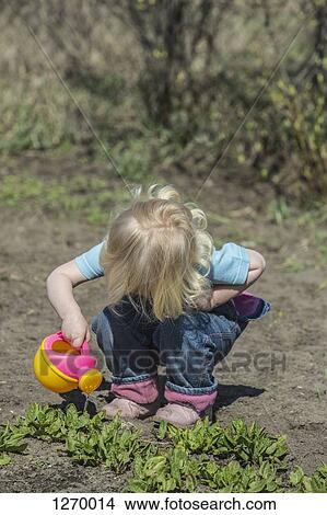 Girl watering plants with her watering can View Large Photo Image Picture - Girl watering plants with her watering can. Fotosearch